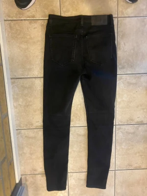 Svarta skinny jeans - Svarta skinny jeans med klassisk femficksdesign och smal passform. Jeansen har hög midja och är tillverkade i stretchigt material för en bekväm känsla. Perfekta för en stilren och modern look.                 Storlek 29/32 priset är ej hugget i sten