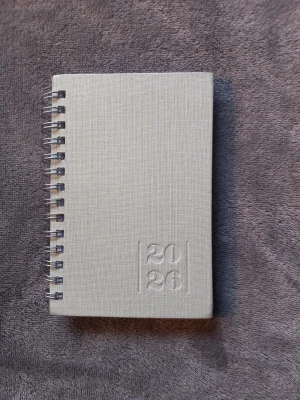 Svag blå kalender 2026 från Burde - Säljer en stilren grå kalender för 2026 från Burde. Kalendern har hård pärm med struktur, spiralbindning och präglat årtal på framsidan. Perfekt för att hålla koll på alla viktiga datum och planer under året.Har skrivit lite i den, men kan sudda + ta bort blad från den.