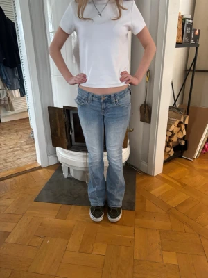 Ljusblå true religion jeans joey - Säljer ett par ljusblå bootcut joey  jeans med låg midja i storlek 23 dem har lite lite slutningar på ena byxbenet längst ner men inget man märker 