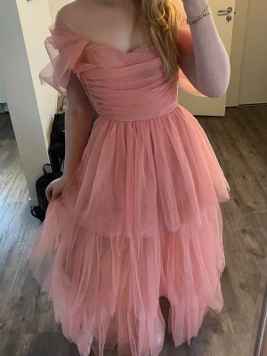 Intressekoll Balklänning Rosa off shoulder - Intressekoll på min fina tyllklänning/ balklänning i en så fin varm/ aprikos rosa färg, som dessvärre är lite för liten och inte går att stänga helt med dragkedjan och inte kan användas. Därav prislapp kvar och oanvänd med nypris på 1500kr som inte säljs längre. Går att ha både off shoulder och med armarna uppe som som då blir som en genomskinlig puff ärm