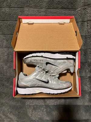 Nike P-6000 - Snygga P-6000 sneakers från Nike i silver och grå mesh med svarta och vita detaljer. Skorna har en sportig design med svart swoosh-logga på sidan och en slitstark sula i vitt och svart.  Vid frågor är det bara skriva och om ni har ett erbjudande kan ni såklart fråga mig!