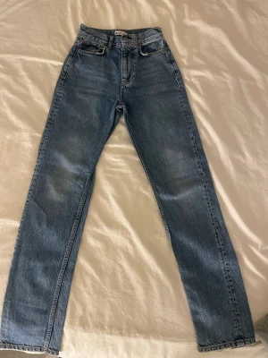 Blå raka high waist jeans - Klassiska blå jeans med hög midja och raka ben. Jeansen har fem fickor och bälteshällor, tillverkade i ett slitstarkt denimtyg. Perfekta för en avslappnad och trendig look.