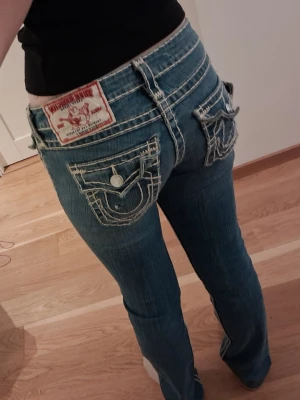 True Religion jeans (pris kan diskuteras) Low rise - Säljer ett par blå jeans från True Religion med tydliga vita kontrastsömmar och stora fickor med lock och knapp bak. PRIS kan diskuteras ✨️💕