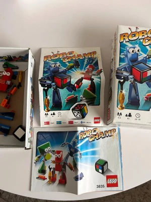 LEGO Robo Champ spel 3835 - Säljer LEGO Robo Champ, ett färgglatt och roligt bygg- och tärningsspel med robotar. Innehåller originalkartong, spelregler och byggdelar i blått, rött, grönt och gult. Perfekt för 2-3 spelare från 6 år. Modellnummer 3835. Aldrig spelat endast byggt ihop robotarna.