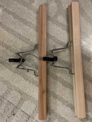 Träbyxgalge med metallklämma - Snygg och praktisk byxgalge i trä med metallklämma. Perfekt för att hänga byxor eller kjolar utan att de får märken. Galgen har två trästavar i olika nyanser och robust metallkonstruktion för extra stabilitet.