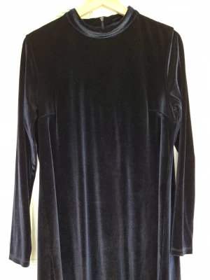 Sammetsklänning från Stylein i mörkblå - Strl medium - Elegant mörkblå sammetsklänning från Stylein. Klassisk passform med hög krage och fint fall. Perfekt för fest, vinter och allt som kräver lite extra.Stylein sammet/velour-klänning i möööörk blå. Den är inte så dammig som den ser ut på bild, det är bara väldigt svårt att ta bilder på materialet! Storlek M.  Material: Polyester Skick: Inte hittat något att anmärka på alls mer än att tvättlappens text knappt syns längre.