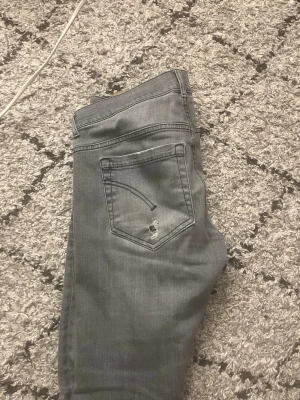 Dondup jeans - Säljer ett par grå skinny jeans med slitningar och hål på både fram- och bak, och en tvättad look som ger en cool och avslappnad.