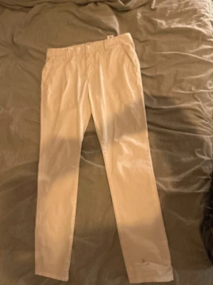 Vita chinos från Dondup - Säljer ett par stilrena vita chinos från Dondup. Byxorna har raka ben, diskreta fickor och klassisk midja. Perfekta för en avslappnad men ändå snygg look. Tillverkade i Italien och har en skön, luftig känsla tack vare linnematerialet.