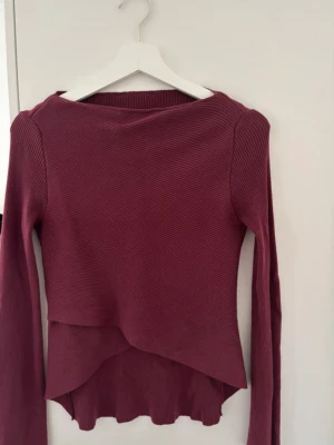 Vinröd ribbad tröja med asymmetrisk kant - Säljer en vinröd långärmad tröja med ribbad struktur och snygg asymmetrisk nederkant. Köpte den utomlands och därför finns inget märke eller storlek, men skulle säga att den är en S💕