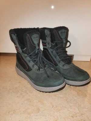 Svarta vinterkängor från Viking - Säljer ett par svarta vinterkängor från Viking med högt skaft, snörning och grov sula. Kängorna har mjukt foder och detaljer i rött och grått. Perfekta för kalla dagar och har en sportig look som passar till många outfits.