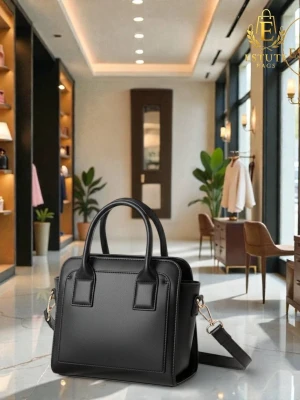 Svart handväska med axelrem - Stilren svart handväska från Estuti Bags med två topphandtag och avtagbar axelrem i matchande färg. Väskan har en boxig form och är tillverkad i slätt konstläder med diskreta sömmar och guldfärgade metalldetaljer. Perfekt för dig som gillar en klassisk och modern look.