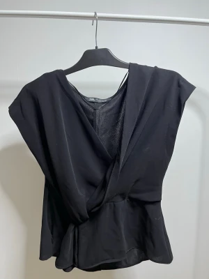 Svart omlottopp från Zara - Snygg svart omlottopp från Zara med v-ringad hals och volang nedtill. Andvänd 2 gånger