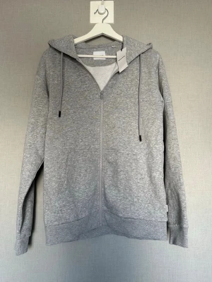 Grå zip-hoodie Jack and Jones  - Säljer denna grå tröjan från Jack and Jones. Tröjan är helt ny och aldrig använd. Hör av dig vid minsta lilla fundering! 💭 