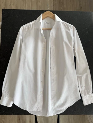 Loro piana skjorta - Säljer en stilren vit skjorta från Loro piana  med klassisk krage och knäppning framtill. Skjortan har lång ärm och är tillverkad i mjuk bomull, perfekt för en clean och tidlös look.