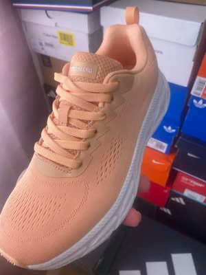 Persikofärgade sneakers stormberg - Snygga sneakers i persikofärg från  med ventilerande mesh-ovandel och vita, tjocka sulor. Skorna har klassisk snörning och en sportig, modern look som passar perfekt till streetwear. Lätta och bekväma för en aktiv vardag.