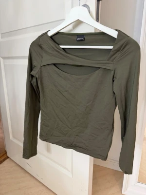 Olivgrön långärmad topp Gina Tricot -  olivgrön topp från Gina Tricot med lång ärm och cut out-detalj vid halsen. 💕