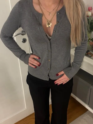 Grå kofta  - Snygg grå kofta från med rund halsringning och knappar framtill. Koftan har en klassisk passform och ribbade muddar vid ärmslut och nederkant. Perfekt att styla med både jeans och kjol.