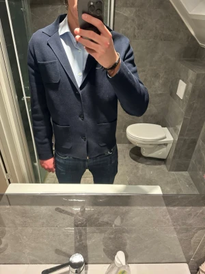 Mörkblå kavaj med fickor  - Stilren mörkblå kavaj med två stora utanpåfickor och en bröstficka från Massimo dutti. Kavajen har enkelknäppning med tre knappar. Jag på bilden är 188cm och bär storlek M. Hör av er vid funderingar eller prisförslag :)