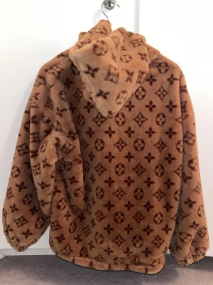 LV-mönstrad kofta/jacka 🤎 FRI FRAKT - Snygg och mysig LV-mönstrad kofta/jacka!💕 Väldigt mjukt & skönt fluffigt material. Bra skick, den enda skavank som finns är kosmetisk på insidan då ena sömmen har gått upp. Det syns inte alls när man har på sig den, och det påverkar inte funktionen av fickorna. Se näst sista bilden. Köpt från storedogdog för flera år sedan för ca 850kr.🤎 Pris går att diskutera!💕 Står ingen storlek men skulle gissa på M, går att justera storleken till viss del med snörena i botten 