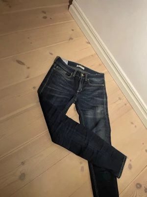 Mörkblå jeans från dondup  - Säljer ett par mörkblå jeans från dondup med klassisk femficksmodell och snygga slitningar. Jeansen har kontrastsömmar, normal midja och smal passform. Materialet är kraftig denim i bomull. Perfekta för dig som gillar en tidlös och stilren look.