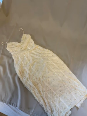 Vit pärlprydd klänning - Superfin vit kort klänning med tunna axelband och täckt av små pärlor. Klänningen har en draperad urringning och är perfekt för dig som vill sticka ut. Materialet känns lyxigt och detaljerna ger en exklusiv känsla. Från Oh Polly. Storlek UK 10, US 6.