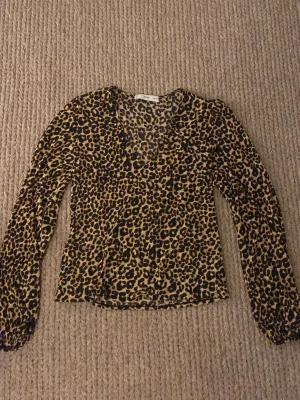 Leopardmönstrad meshblus från Mango - Trendig blus i meshmaterial med leopardmönster från Mango. Blusen har v-ringning och långa ärmar, tunt material funkar både sommar och vinter. Som ny bara änvänd några få gånger. Skriv för mer bilder och info.