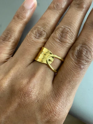 s925 sterling Guldfärgad ring i unik design - Cool ring i guldfärgat material med en modern, böjd form och en öppen design. Ringen har en blank finish och är märkt med 925, vilket tyder på att den är i förgyllt silver. Perfekt för dig som gillar statement-smycken och vill sticka ut.