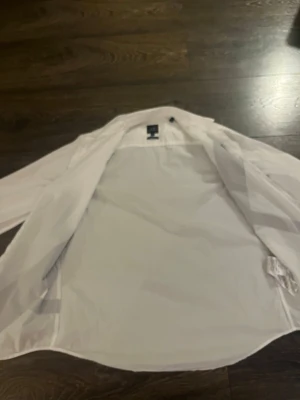 Vit skjorta från Armani Exchange - Snygg vit skjorta från Armani Exchange med klassisk krage och lång ärm. Skjortan har en stilren design och är tillverkad i ett tunt, lätt material som känns bekvämt mot huden. Perfekt för dig som gillar en clean och modern look.