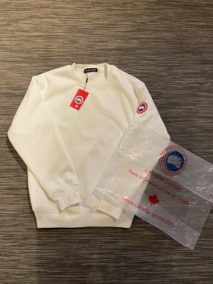 Vit Canada Goose tröja - Säljer en snygg tröja från canada goose! Tröjan är i mycket bra skick och har inga defekter. Storlek M. Om ni har några frågor så är de bara att höra av er!😊
