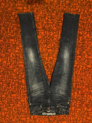 Mörkblå skinny jeans EXTREME FLEX - Snygga mörkblå skinny jeans med EXTREME FLEX-tyg för extra stretch och komfort. Jeansen har slitna detaljer och ljusare partier på låren för en cool look. Perfekta för dig som gillar tajt passform och vill ha maximal rörelsefrihet.