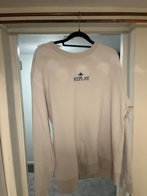 Ljusgrå sweatshirt från Replay - Säljer en stilren ljusgrå sweatshirt från Replay med broderad logga i blått på bröstet. Tröjan har rund halsringning, långa ärmar och ribbade muddar vid ärmslut och nederkant. Perfekt för en avslappnad och trendig look. Nypris 1000kr