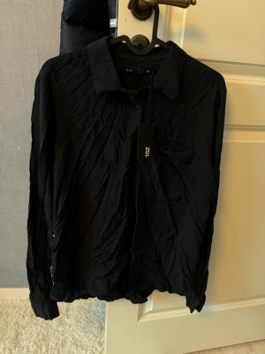 Svart skjorta  - Svart skjorta från lager 157. Strl S, mjukt och skönt material. Ny med lappar kvar. Lite skrynklig just nu men det går bort genom att stryka / tvätta den 