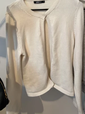 Vit kofta från Gina Tricot - Snygg vit kofta från Gina Tricot i storlek XS. Koftan har rund halsringning, ribbade muddar och en knapp upptill. Perfekt att slänga över en topp för en clean look. Materialet känns mjukt och bekvämt.