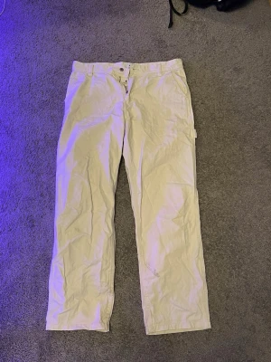 Beige/vita cargobyxor med raka ben - Snygga beige cargobyxor med raka ben och klassisk passform. Byxorna har flera fickor och är tillverkade i ett mjukt bomullstyg. Perfekta för en avslappnad streetwear-look.