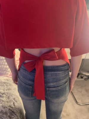 Röd croppad topp med knyt i ryggen - Från Gina tricot. Trendig röd topp med halvlånga ärmar och snygg knytning i ryggen. Toppen har en enkel, stilren design och är tillverkad i mjukt bomullsmaterial. Perfekt för dig som vill ha en cool och bekväm look.