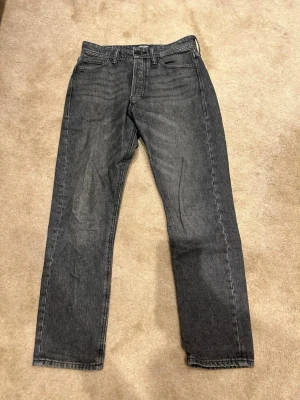 Svarta jeans från Jack&Jones  - Säljer ett par svarta jeans från Jack&Jones i modellen loose/chris i storlek 29/30. De har en rak passform och klassisk femficksdesign. Jeansen har en diskret tvättad look och är tillverkade i denim. Pris kan diskuteras!! Vid minsta fundering är det bara att höra av 