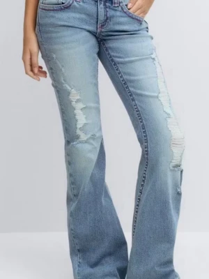Ljusblå bootcut jeans med slitningar - Säljer ett par ljusblå bootcut jeans med kraftiga slitningar framtill och broderade detaljer på bakfickorna i rosa. Jeansen har hög midja och klassisk femficksdesign. Tillverkade i denim med en cool vintagekänsla. de är från gina 14+, INGA skador nästan helt nya. säljer pga att de är lite små på mig.