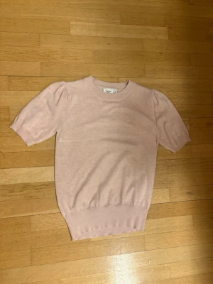 Ljusrosa puffärmstickad tröja - Supersöt ljusrosa stickad tröja med puffärmar och ribbade muddar. Tröjan har rund halsringning och korta ärmar, perfekt för en trendig och feminin look. Materialet känns mjukt och bekvämt mot huden. Använd fåtal gånger. Priset går att diskutera. Frakt ingår ej! Storlek xs men passar s också.