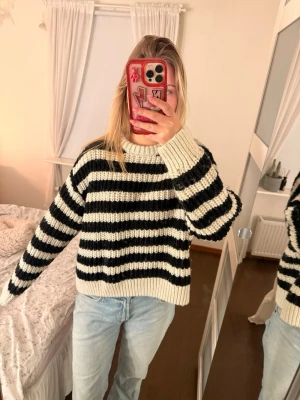 Randig stickad tröja i svart och vitt - Säljer en chunky stickad tröja med breda svarta och vita ränder. Tröjan har en avslappnad passform, rund halsringning och långa ärmar. Perfekt för dig som gillar en trendig och bekväm stil.