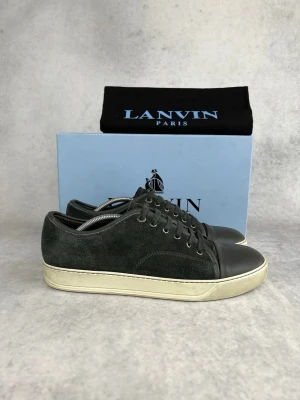 Lanvin svarta sneakers i mocka - Stilrena svarta sneakers från Lanvin med ovandel i mocka och tåparti i slätt läder. Skorna har vita sulor och klassisk snörning. Perfekta för dig som gillar en clean och exklusiv look.