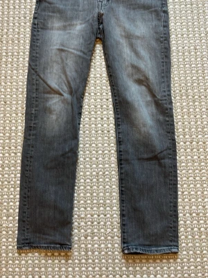 Mörkgrå raka jeans - Snygga mörkgrå jeans med rak passform och klassisk femficksdesign. Jeansen har subtila slitningar och är tillverkade i ett mjukt denimtyg som ger en avslappnad look. Perfekta till sneakers eller boots för en cool vardagsstil. Gylfen är däremot sönder och kan lämnas in och bli fixad snabbt! 