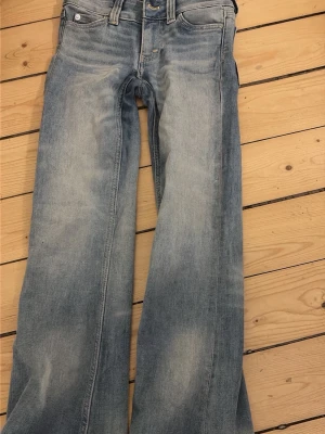 Ljusblåa Cheap Monday jeans bootcut - Säljer ett par ljusblåa jeans från Cheap Monday med bootcut-modell och klassisk femficksdesign. Jeansen har en snygg tvättad look och en stor vit logotyp-patch bak i midjan. Perfekta för dig som gillar avslappnad stil.