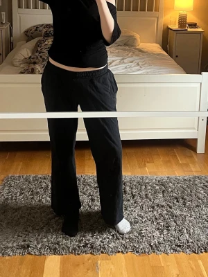Svarta vida mjukisbyxor - Säljer ett par svarta mjukisbyxor med bred resår i midjan och raka, vida ben. Sköna och enkla att matcha till olika outfits. Perfekta för chill dagar hemma eller när du vill ha det bekvämt. Materialet känns mjukt och följsamt.