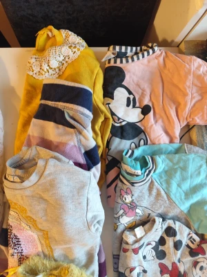 Tröjor och Sweatshirts packet 122/128 - Flera tröjor i olika färger och stilar, bland annat med Disney-motiv som Musse Pigg och Kajsa Anka, samt en gul fluffig tröja med text. Här finns både randiga och enfärgade tröjor, vissa med spetsdetaljer och broderier. Perfekt för dig som gillar färg och lekfulla prints.Du är varmt välkommen att kika på mina andra annonser. Sammanfrakt