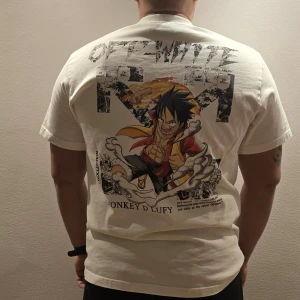 Off-White x One Piece T-shirt vit - Vit T-shirt från Off-White med stor färgglad Monkey D. Luffy-tryck från One Piece på ryggen och mindre tryck på bröstet. 