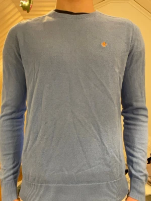 Blå tröja från Morris - Säljer en snygg blå tröja från Morris i 100% Pima Cotton. Tröjan har en broderad orange detalj på bröstet och långa ärmar. Perfekt för en stilren look. Hör av dig vid intresse! Två stycken defekter som inte syns. (Bild 4 och 5) nypris är 1200. Defekterna är i armhålorna 