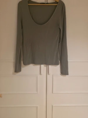 Ljusgrå långärmad topp - En enkel och stilren ljusgrå långärmad topp med djup rundringning. Aldrig använd 