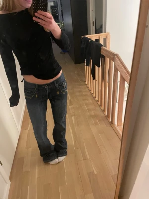 Mörkblå bootcut jeans med brodyr - Säljer ett par mörkblå bootcut jeans med coola gula broderier på bakfickorna och nitar på linningen. Jeansen har låg midja och klassisk femficksmodell. Perfekta för dig som gillar en avslappnad men ändå edgy stil. Köpte på plick för 300kr. Pris kan diskuteras!💗