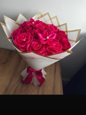 Bukett med röda konstblommor - Snygg bukett med röda konstblommor i satinliknande material, dekorerad med vita pärlor och inslagen i vitt och guldigt papper. Buketten är knuten med ett rött band och hjärtformad dekoration. Perfekt som present eller dekoration.