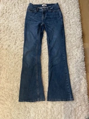 Blå bootcut jeans med hög midja - Ett par klassiska blå bootcut jeans med medel låg midja och femficksmodell. Jeansen har utsvängda ben och är tillverkade i ett robust denimtyg. Perfekta för en avslappnad och trendig look.💕💕